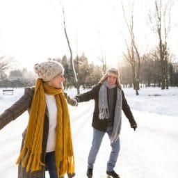 Older woman and man in sunny winter nature ice skating.
