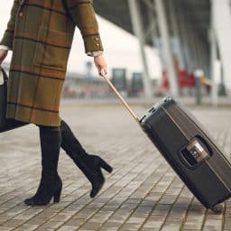 Woman carrying her bag and plane ticket as she heads into the airport.
