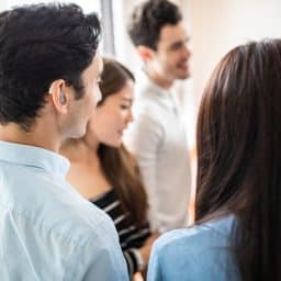 Young man with hearing aids talking with a group of friends.