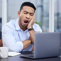 Man yawning in front of his computer.