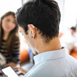 Man with hearing aid looks at phone