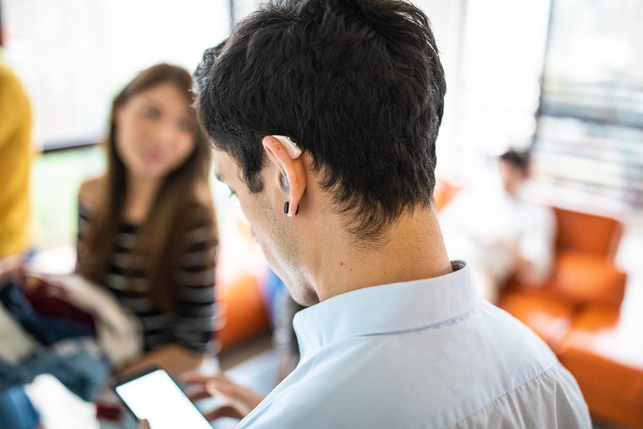 Man with hearing aid looks at phone