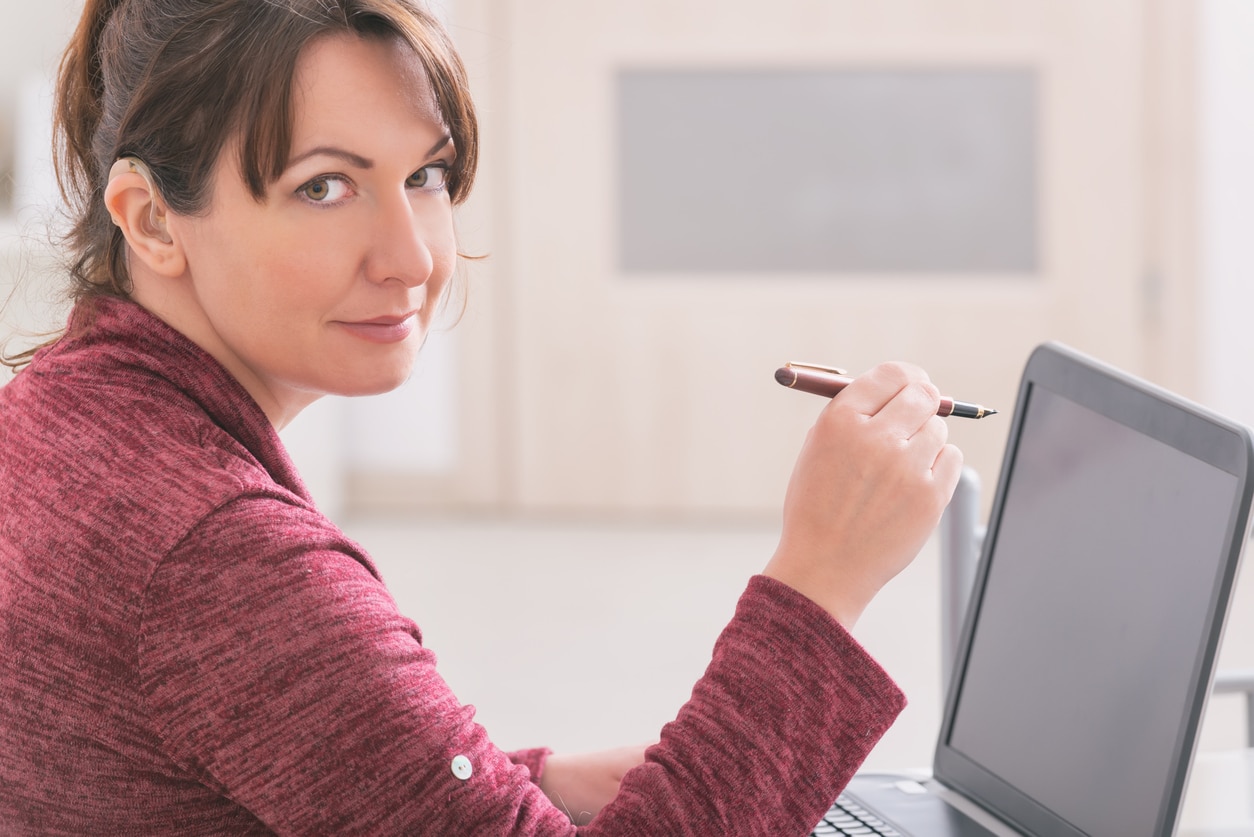 Woman wearing a hearing aid using her laptop