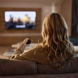 Back view of relaxed woman watching TV at home.