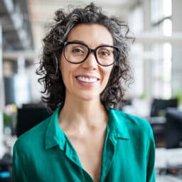Close-up portrait of smiling businesswoman standing in office.