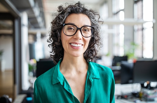 Close-up portrait of smiling businesswoman standing in office.