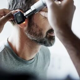 Doctor checking a man's ear.