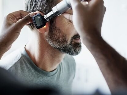 Doctor checking a man's ear.
